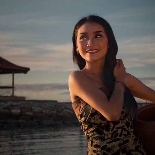 Beautiful Balinese girl on the beach at sunrise.